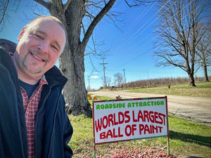 Scott standing in front of the sign for the World's Largest Ball of Paint.